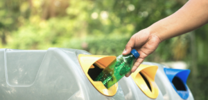Person putting green plastic bottle in recycling bin