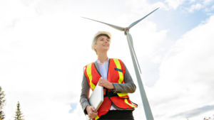 Woman holding a laptop with a wind turbine in the background